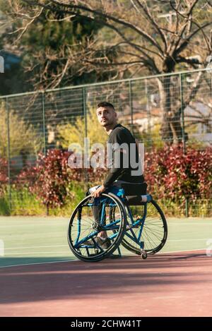 Young handsome man in wheelchair at basketball playing ground Stock Photo