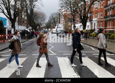 Tourists walk on a zebra crossing to recreate the Abbey Road album cover by The Beatles outside the Abbey Road recording studio in London, Britain March 9, 2016. George Martin, known as 'the fifth Beatle' for his work in shaping the band that became one of the world's most influential music forces, has died at the age of 90. REUTERS/Neil Hall