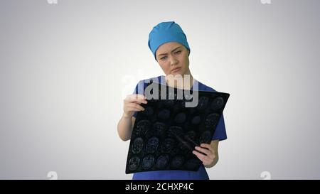 Female doctor looking at brain tomography on gradient background Stock Photo