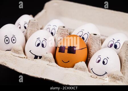 Closeup shot of eggs with funny faces in the package Stock Photo