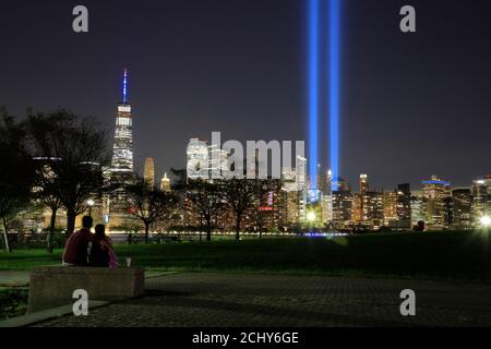 The annual 'Tribute in Light' light beams project in night sky of Lower Manhattan to memorial Sept.11 terrorist attacks victims with people viewing it in Liberty State Park in foreground.New Jersey.USA Stock Photo