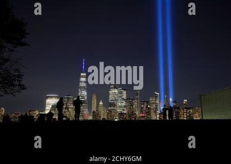 The annual 'Tribute in Light' light beams project in night sky of Lower Manhattan to memorial Sept.11 terrorist attacks victims with people viewing it in Liberty State Park in foreground.New Jersey.USA Stock Photo