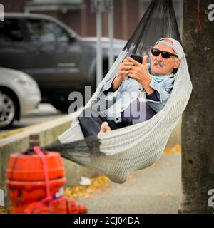 Man relaxing in hammock on busy street, Stock Photo