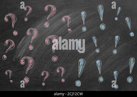 Hand drawn question marks  on the left and exclamation marks on the right.   Illustration are drawn in chalk on a blackboard. FAQ or discussion concep Stock Photo