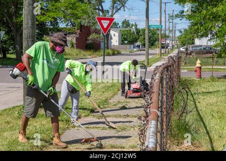 Detroit, Michigan - Workers from the Detroit Grounds Crew clean up an overgrown sidewalk. Stock Photo