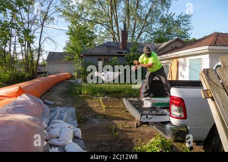 Detroit, Michigan - A worker places sandbags to shore up an orange 'Tiger Dam' near a canal which connects to the Detroit River and Great Lakes. The p Stock Photo