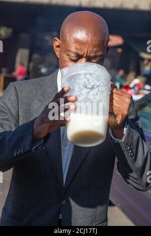 African male drinking Umqombothi - a South African beer made from maize Stock Photo