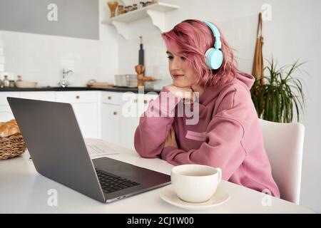 Young hipster woman with pink hair wearing headphones using at home. Stock Photo
