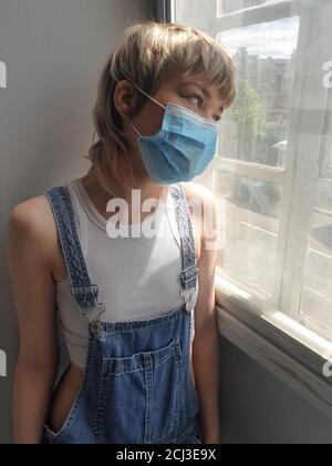 Girl isolated and alone at home wearing medical mask Stock Photo