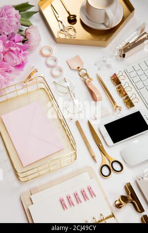 Neatly arranged office stationery with modern gadgets, devices, coffee and flowers on white desk. Stock Photo
