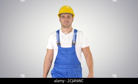 Walking worker in yellow helmet on gradient background. Stock Photo