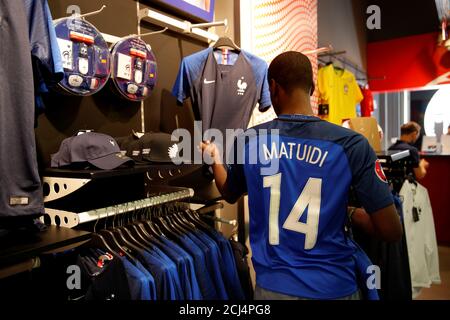 a man wearing an official france team soccer jersey with the name of player blaise matuidi looks at jerseys at nsh foot store in paris france several days before the soccer world