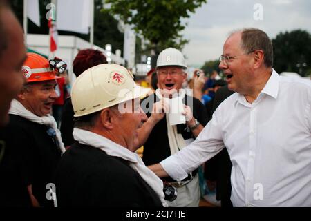 Peer Steinbrueck (R), the Social Democratic party (SPD) candidate in the upcoming general elections, sings with miners at his party's 150-year-anniversary celebration, the Deutschlandfest, at Brandenburg Gate in Berlin, August 17, 2013. Steinbrueck will challenge German Chancellor Angela Merkel (CDU) in Germany's general elections on September 22.   REUTERS/Thomas Peter (GERMANY - Tags: POLITICS ELECTIONS)