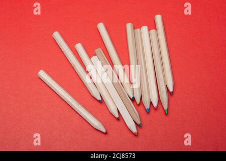 Colored pencils on red background. Many different colored pencils. Stock Photo
