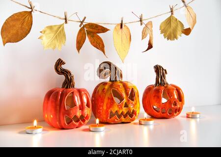 Ceramic Jack Lanterns and autumn leaves garland. Halloween composition. Home decor Stock Photo