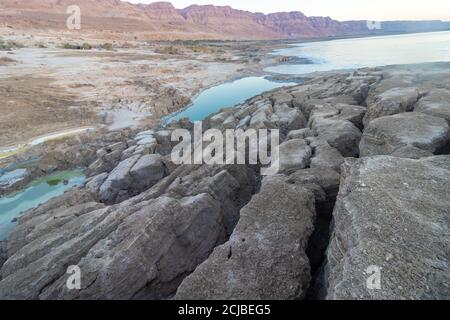 Cracks in the ground due to the scorching heat against the background of sinkholes in the Dead Sea, Israel. Stock Photo