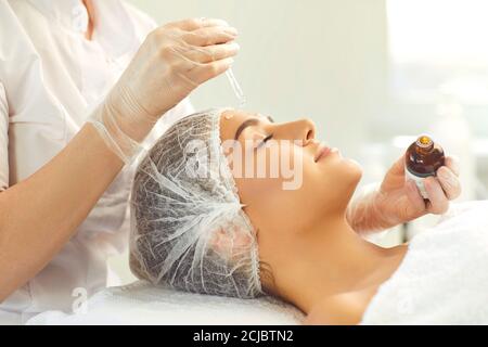 Professional cosmetician using pipette to apply moisturizing serum on client's face Stock Photo