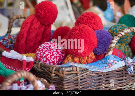 Close up of wicker backet full of knitted wool hats. Christmas fair outdoors. Stock Photo