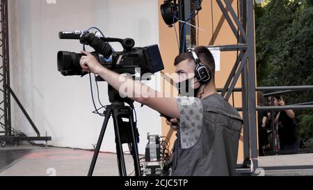 Young male videographer in a protective medical mask filming a city event during coronavirus covid-19. Stock Photo