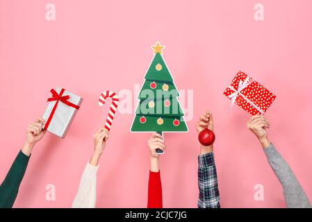 Hands holding gift boxes and colorful Christmas decorating items on pink isolated background Stock Photo