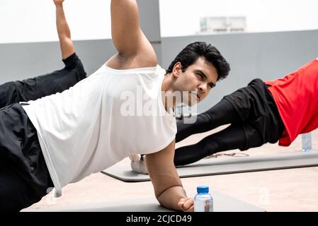 Group of athletic men doing side plank morning workout exercise outdoors on rooftop floor Stock Photo