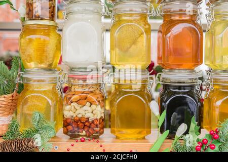 Christmas fair - farious sorts of honey in glass jar displayed on window shop. Tasty and healthy dessert. Stock Photo
