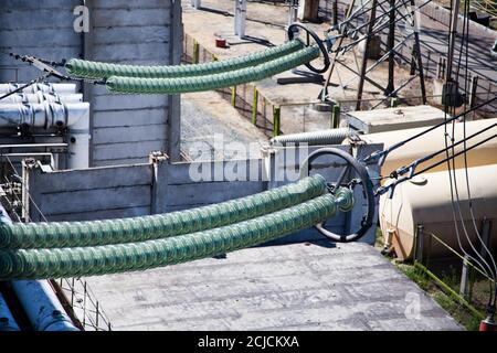 Close-up of glass isolators on electric transformer station. Glass insulators on high-voltage wires (cables) on generated plant. Powerhouse Stock Photo