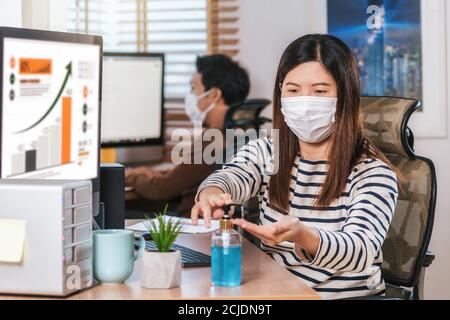 Asian woman worker using hand sanitizer for cleaning her hand when working  with computer in Home office when Covid-19 pandemic, Coronavirus outbreak, Stock Photo