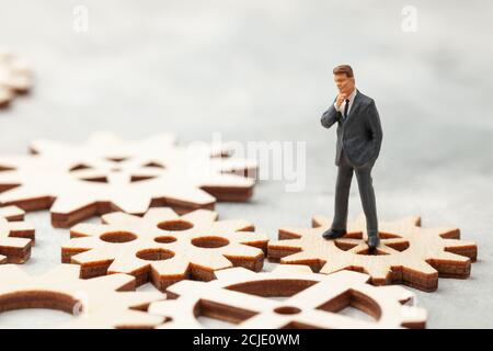 Business Analysis. Audit of the company. A businessman in a suit stands on gears as a symbol of business processes in the company. Stock Photo