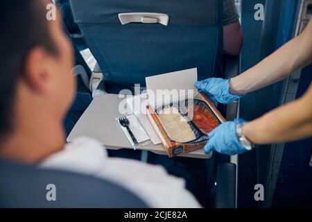 Air hostess putting meal on table gently in front of man Stock Photo