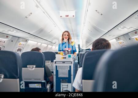 Air stewardess serving food on the board commercial airplane Stock Photo