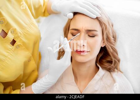 Woman getting injection procedure for tightening and smoothing wrinkles on forehead face skin. Beauty salon care Stock Photo