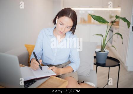 Concept office work home. Woman teacher in headphones greets in video chat with laptop students Stock Photo
