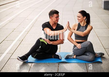 Happy couple doing stretching after workout outdoors Stock Photo