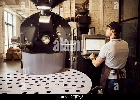 Professional male roaster using industrial coffee roasting machine Stock Photo