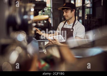 Handsome young man controlling work of coffee roasting machine Stock Photo