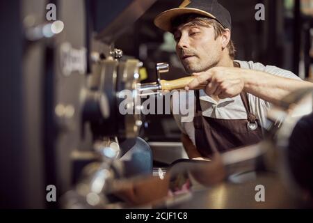 Professional roaster using coffee roasting machine at factory Stock Photo