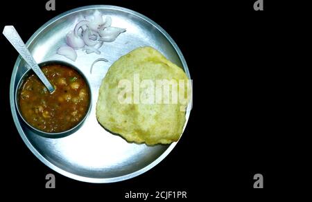 Chole Bhature or Chick pea curry and Fried Puri served in a plate and bowl over a black background with blank space for text Stock Photo