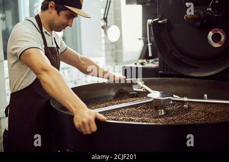 Handsome male worker using professional coffee roasting machine Stock Photo
