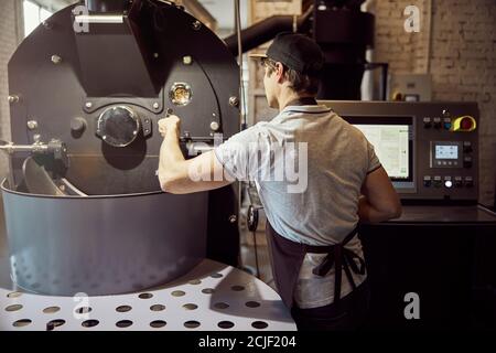 Professional roaster using industrial coffee roasting machine Stock Photo
