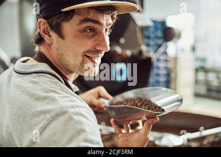 Handsome young man holding scoop with coffee beans Stock Photo