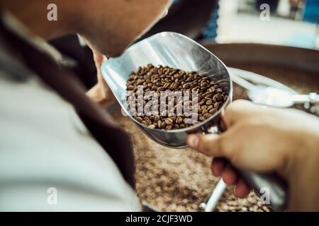 Young man smelling freshly roasted coffee beans Stock Photo