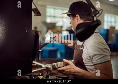 Male worker using industrial coffee roasting machine Stock Photo