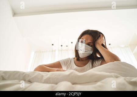 Thoughtful sick young woman sitting in quarantine Stock Photo
