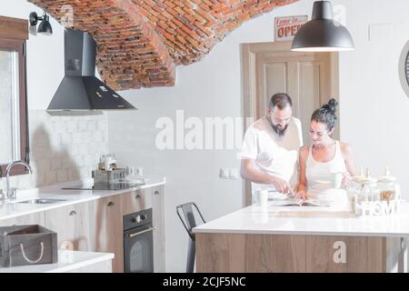 young couple reading a magazine at home while having coffee at home in the morning Stock Photo