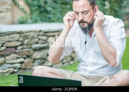 hipster guy with a beard putting on headphones to make a video call Stock Photo