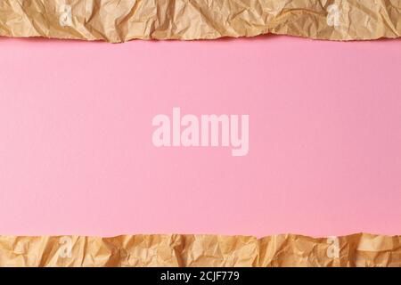 Torn crumpled recycled brown paper on light pink colored paper background inside Stock Photo