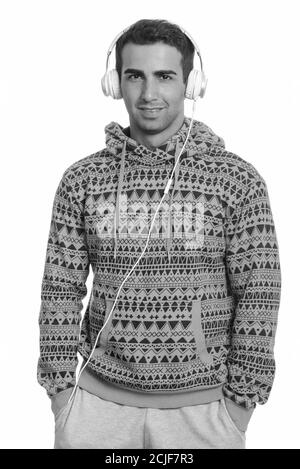 Studio shot of happy young handsome Persian man listening to music Stock Photo