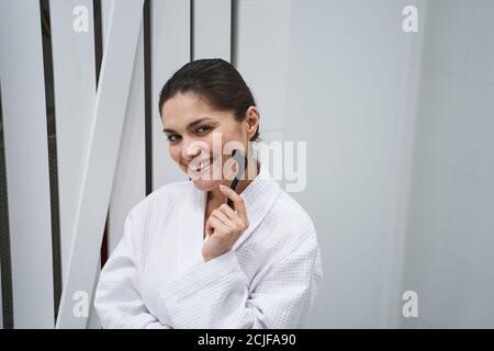 Smiling pleased woman doing a facial massage Stock Photo