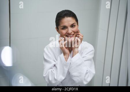 Smiling woman rubbing a face cream into her skin Stock Photo